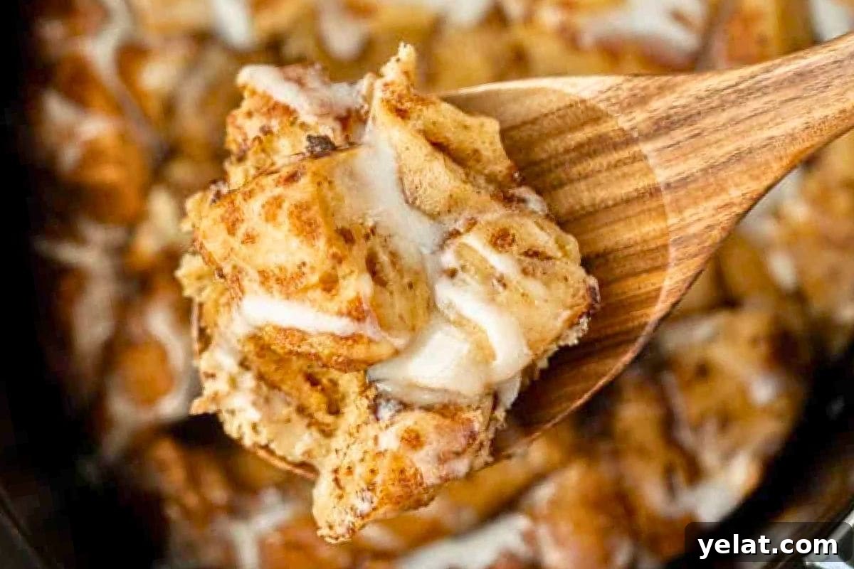 12 Crowd-Pleasing Easter Crockpot Recipes for a Stress-Free Holiday 2 A wooden spoon serving a slice of cinnamon roll casserole, showcasing its fluffy texture and creamy icing.