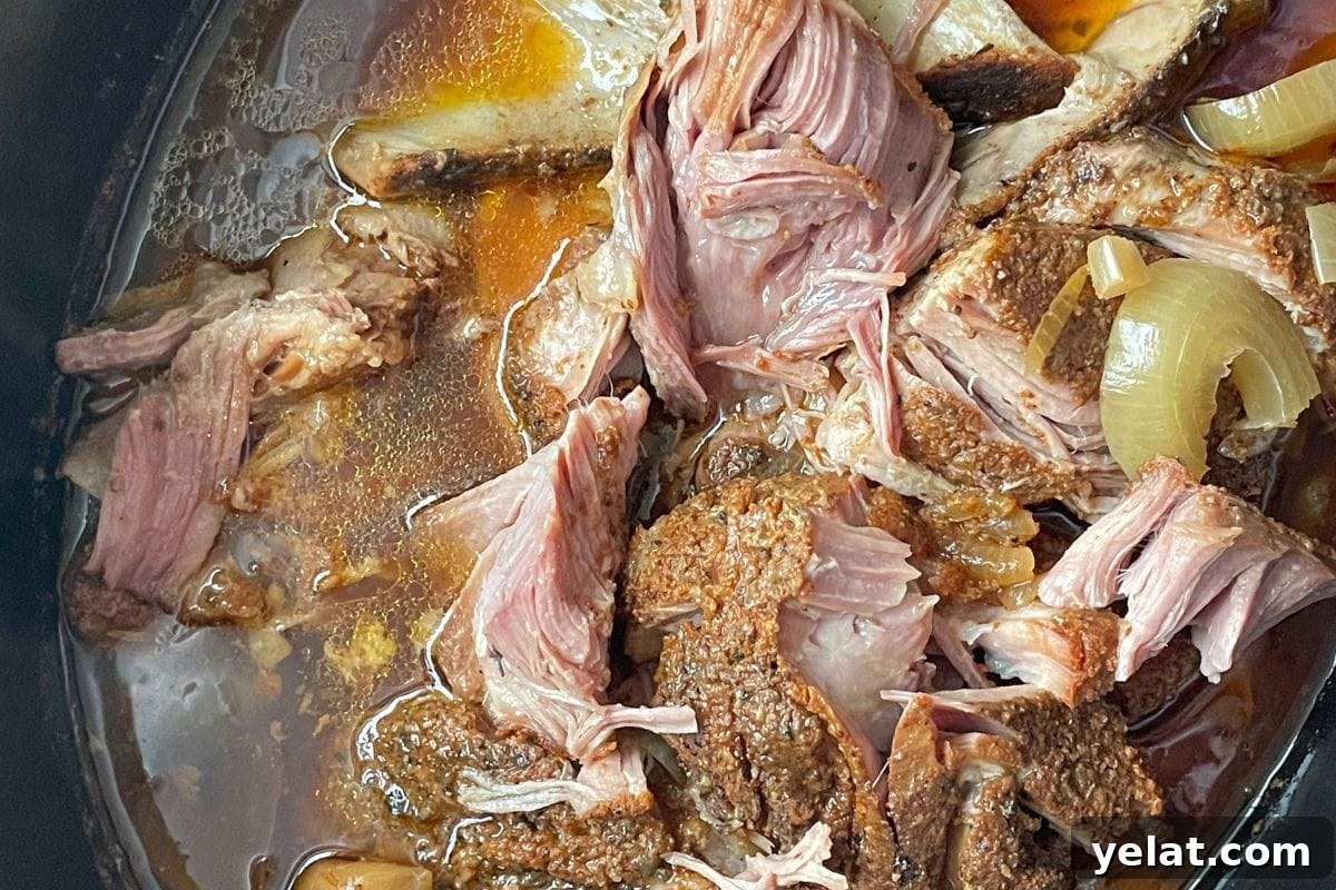 12 Crowd-Pleasing Easter Crockpot Recipes for a Stress-Free Holiday 11 Close-up of tender slow-cooked pork with onions in broth, showcasing the succulent textures and rich colors.