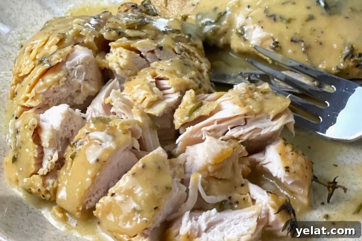 12 Crowd-Pleasing Easter Crockpot Recipes for a Stress-Free Holiday 5 A close-up of sliced chicken breast topped with a creamy herb sauce on a plate with a fork.