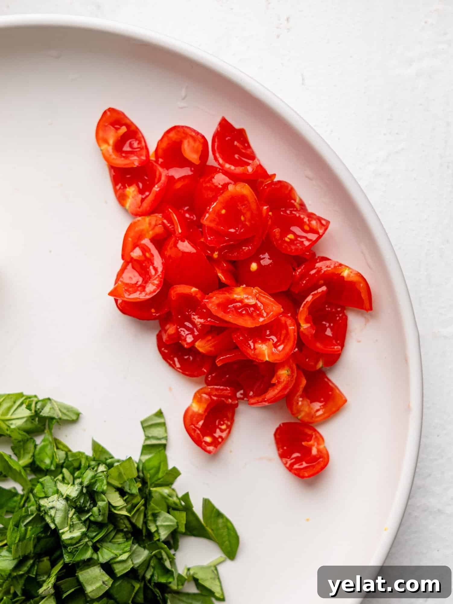 Cherry tomatoes cut into quarters with seeds removed on a white plate.