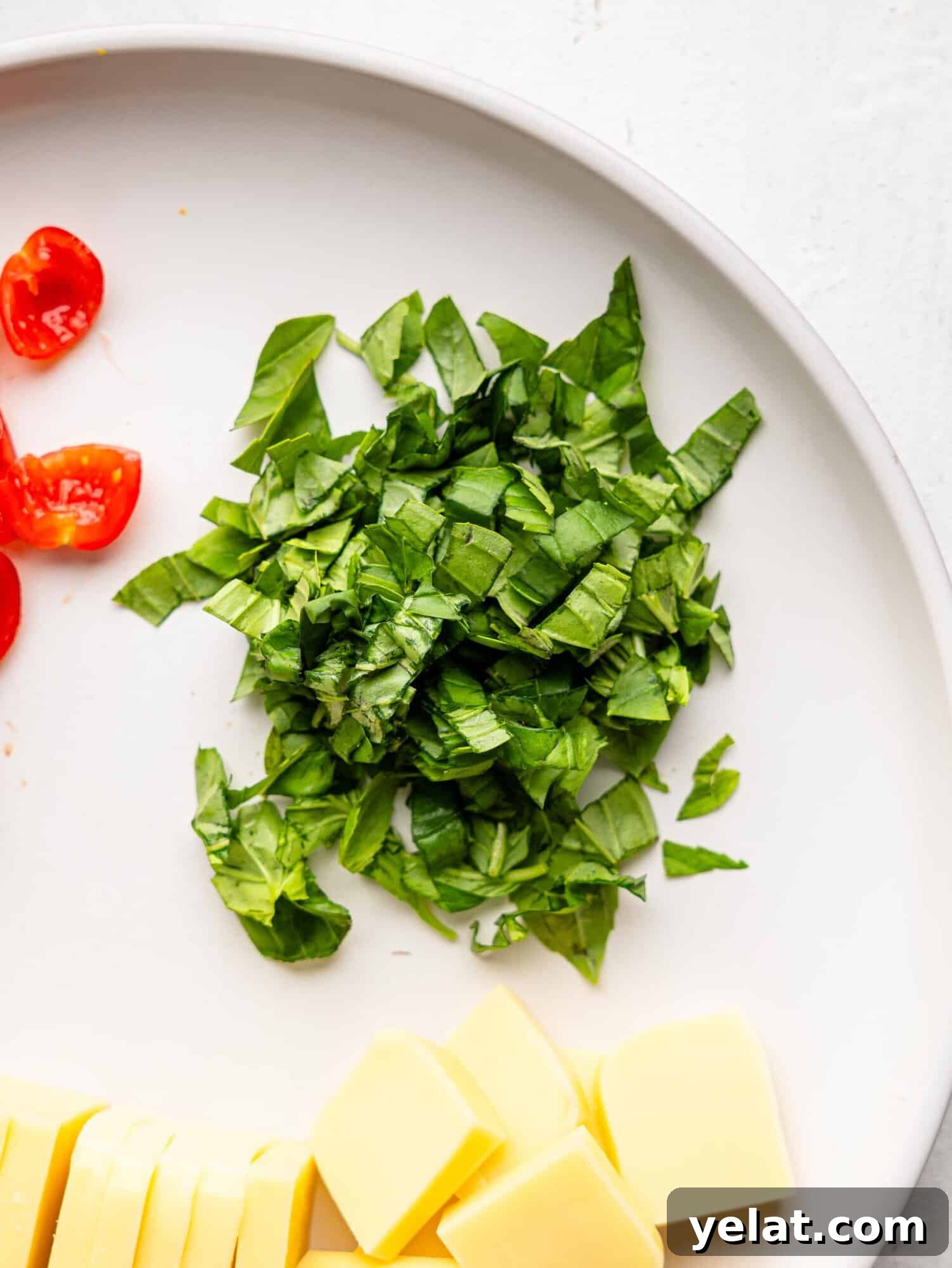 Roughly chopped basil on a white plate.