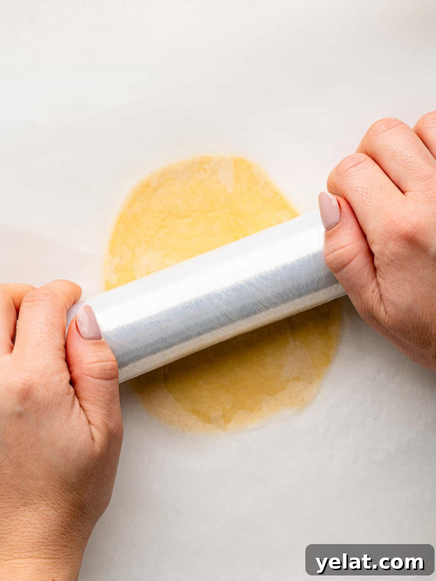 Rolling out an empanada disk with clingwrap.