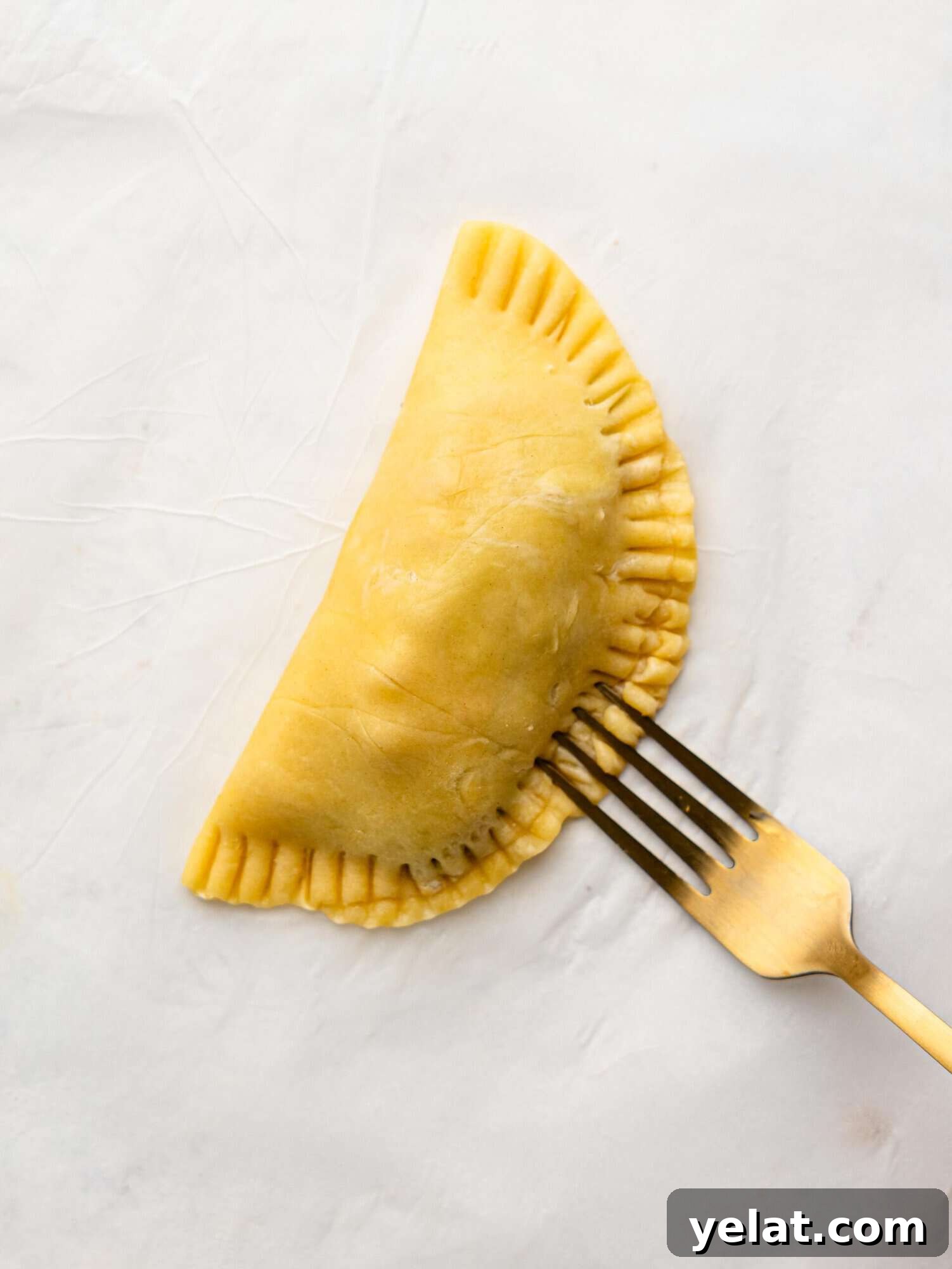 Crimping an empanada with a fork.