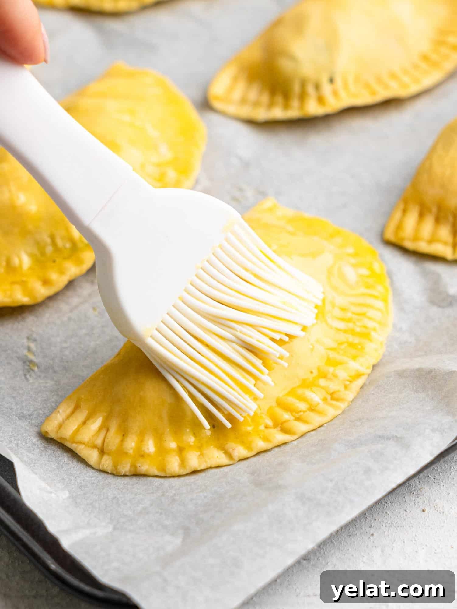 Brushing an empanada with an egg wash.