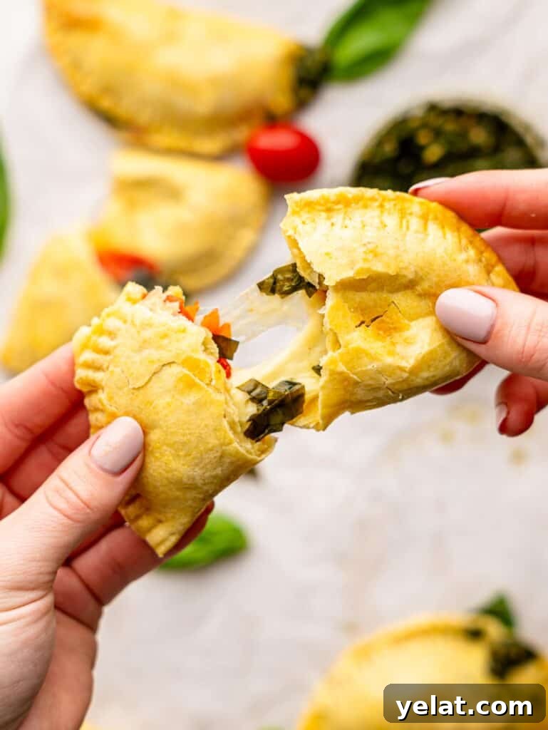 Someone tearing a caprese empanada in half.