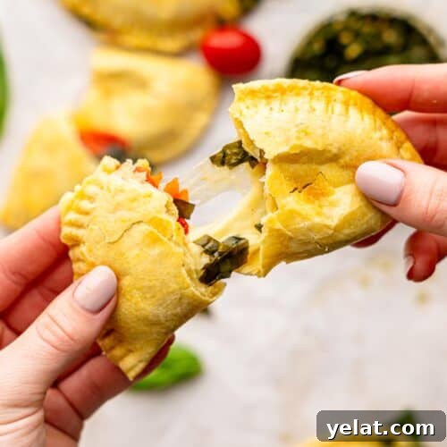 Someone tearing a caprese empanada in half.