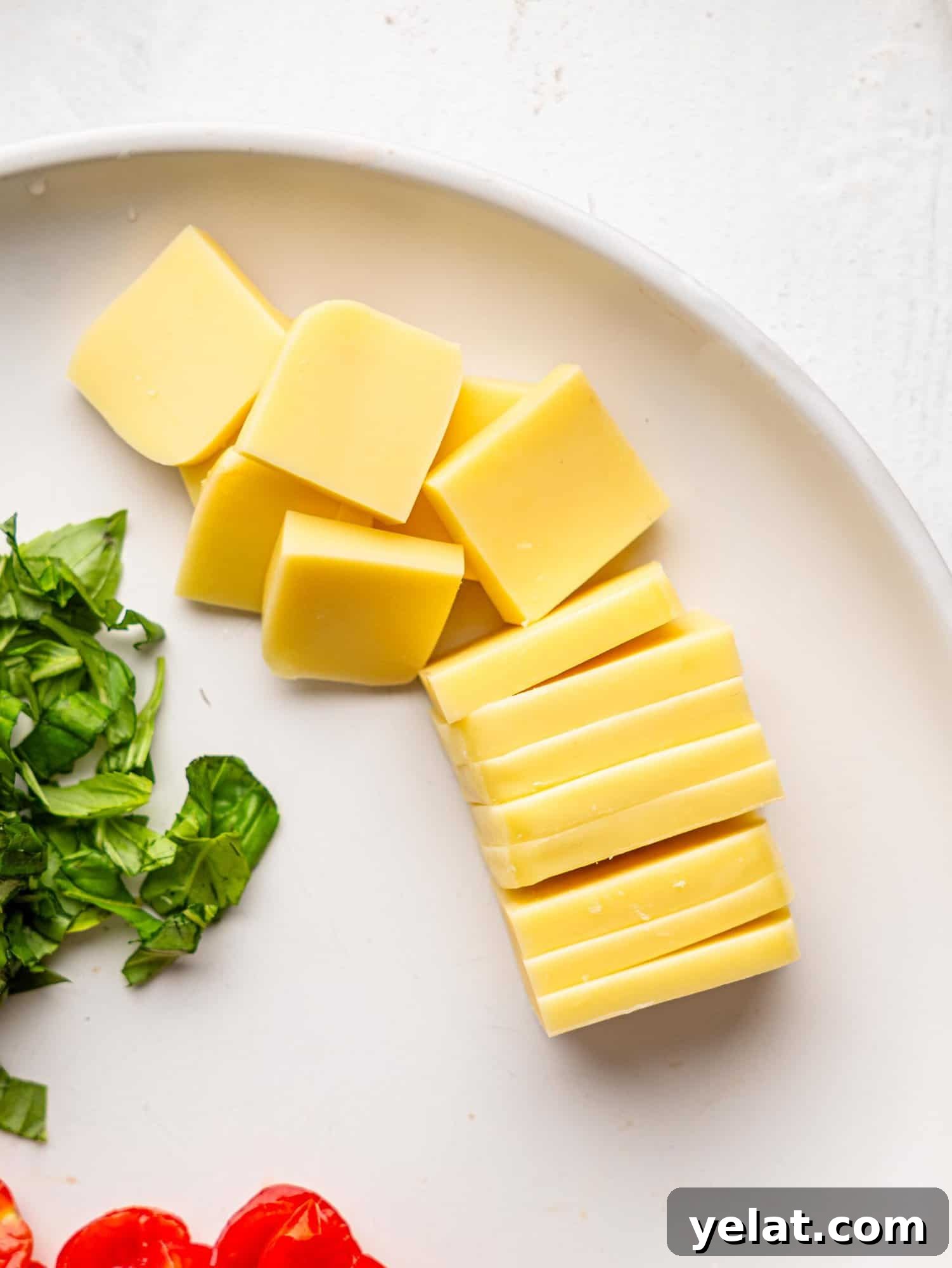 Mozzarella sliced into small pieces on a white plate.
