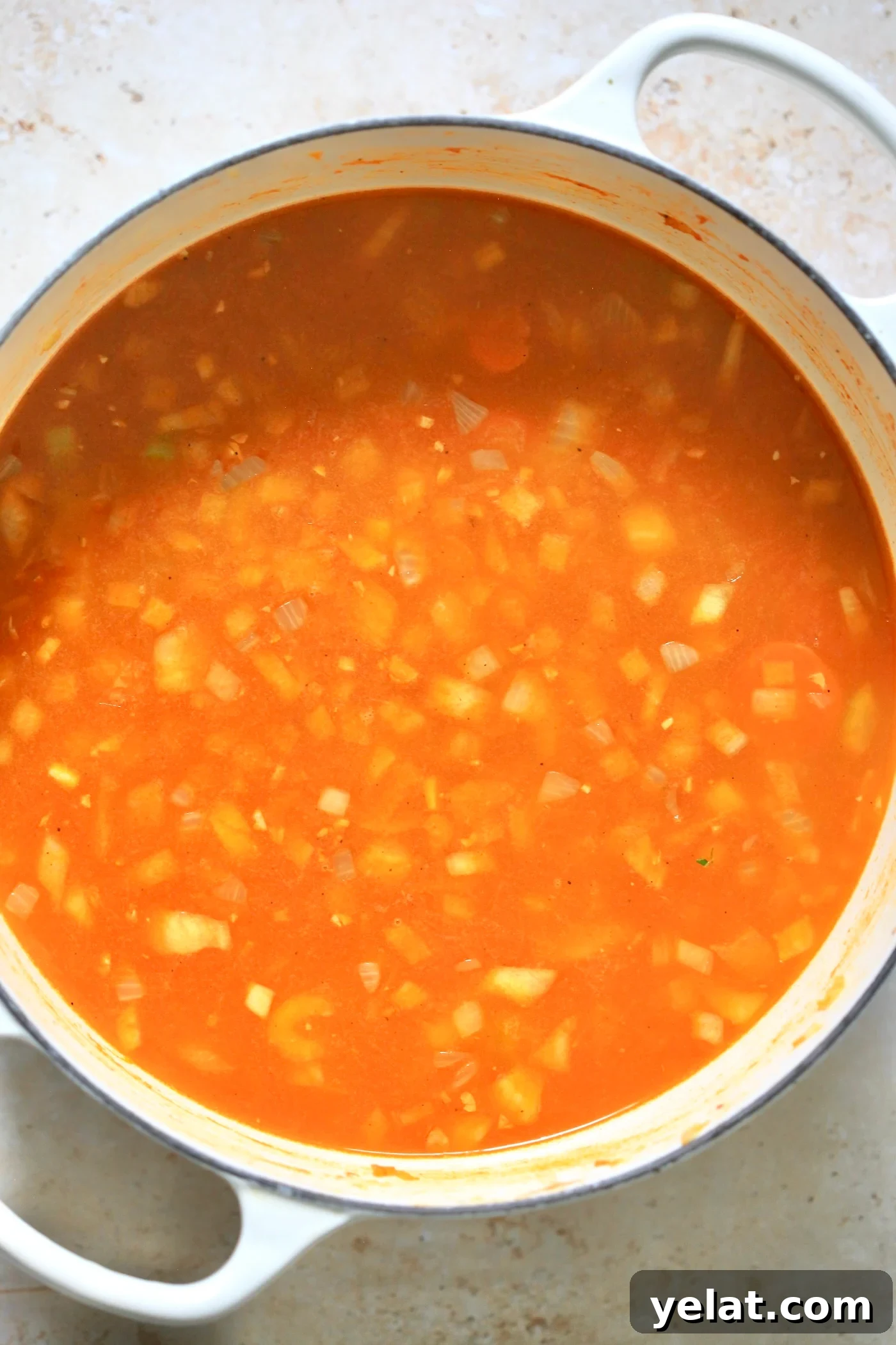 Hearty Carrot and Red Lentil Soup Recipe for Comfort and Flavor 5 red broth with onions in white pot.