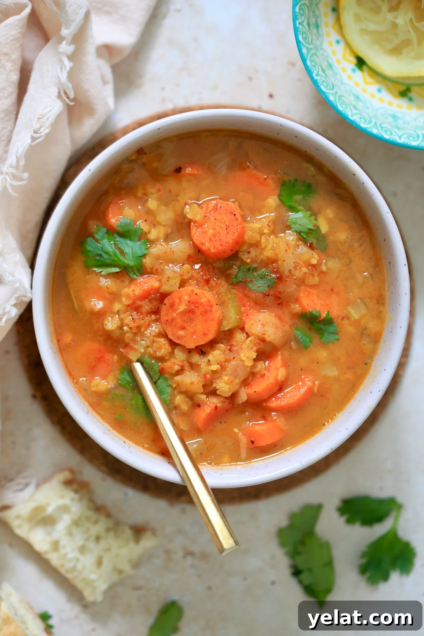 Hearty Carrot and Red Lentil Soup Recipe for Comfort and Flavor 7 bowl of lentil soup with carrots and gold spoon.