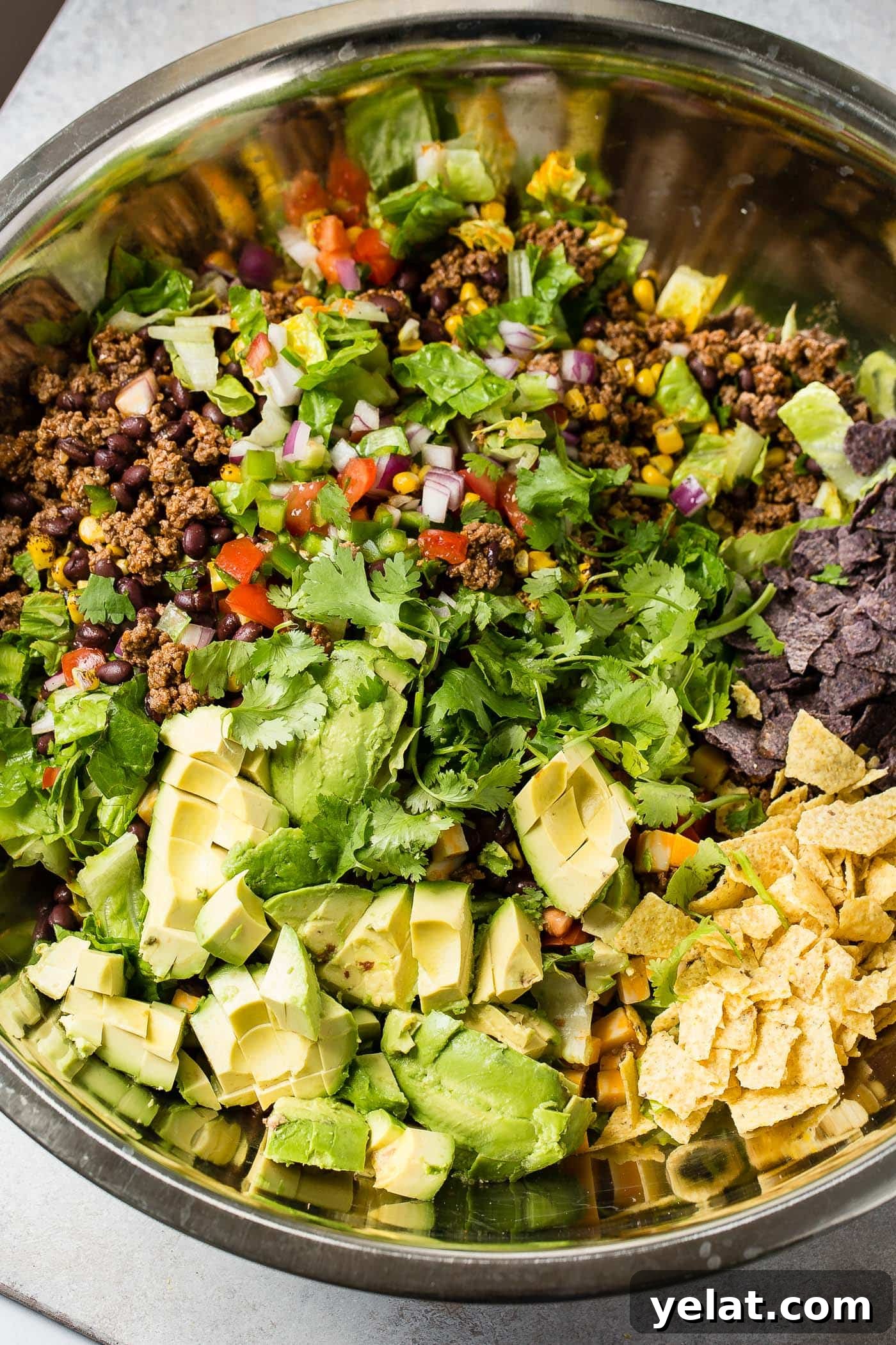 Tex-Mex Chopped Ground Beef Taco Salad Recipe 9 A close-up of tex‑mex taco salad. You can see the fresh lettuce, tomatoes, corn, chips, and taco meat.