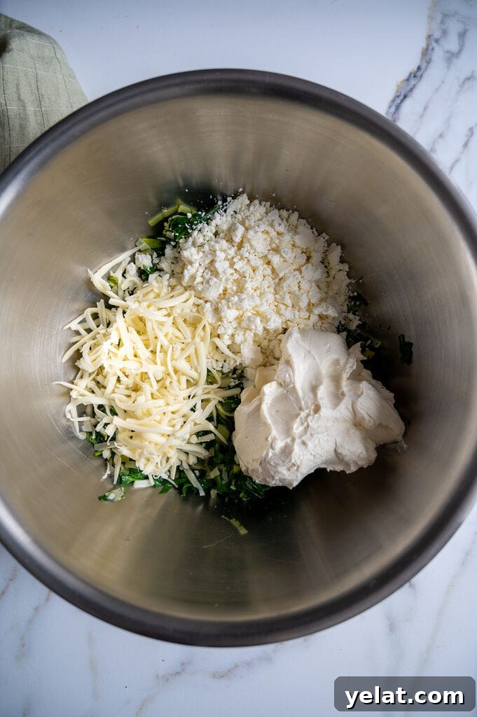 Combining the sautéed spinach with the 3 cheeses: Mozzarella, feta cheese, and cream cheese.
