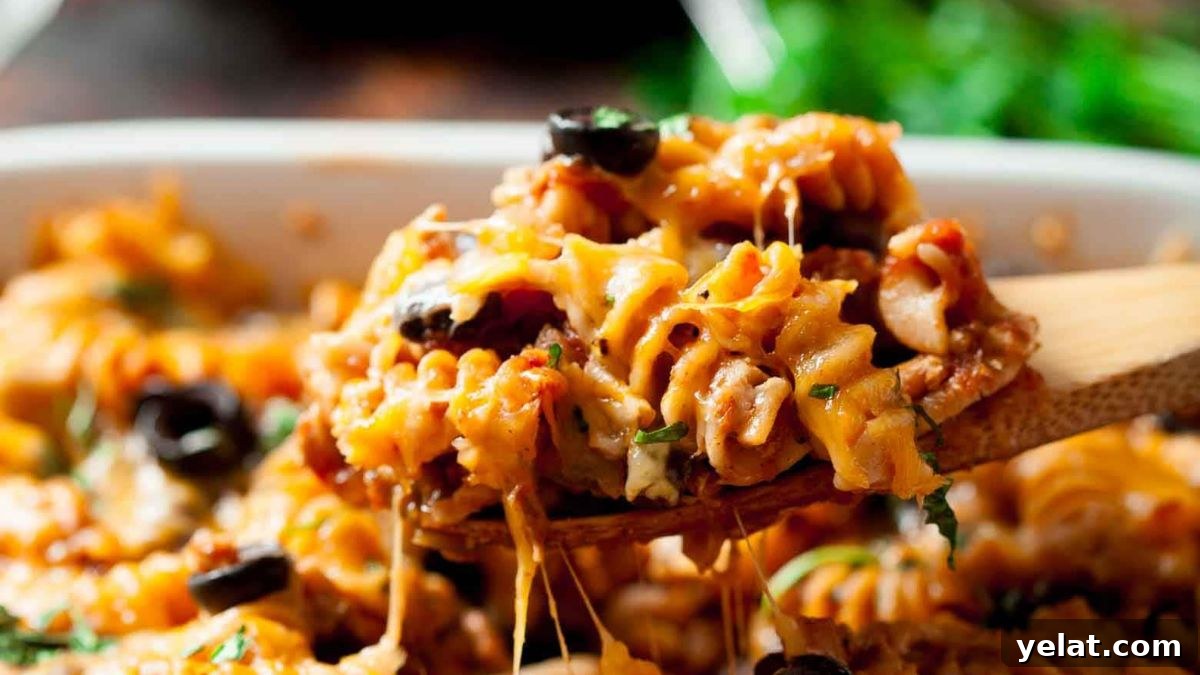 Scoop of Mexican pasta bake on a wooden spoon.