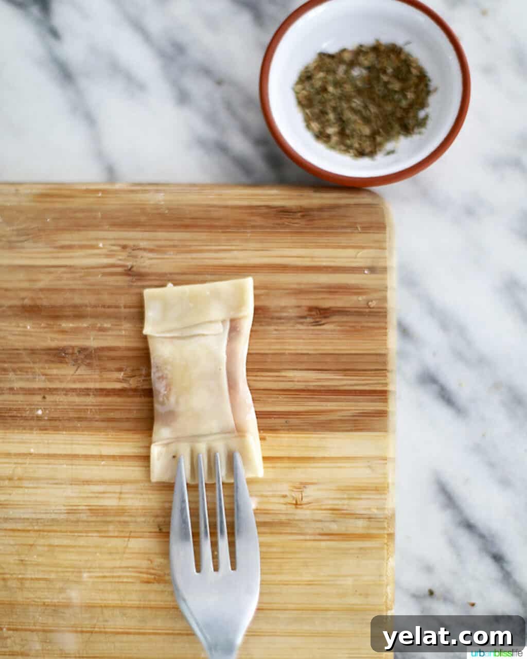 a fork securing edges of air fryer pizza rolls on a cutting board