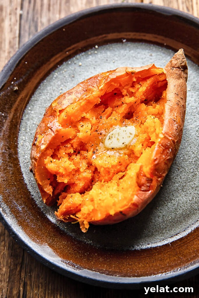 Crispy Air Fryer Sweet Potato (Simple Baked Style) 2 Close up shot of a cut open baked sweet potato topped with melted butter on a plate