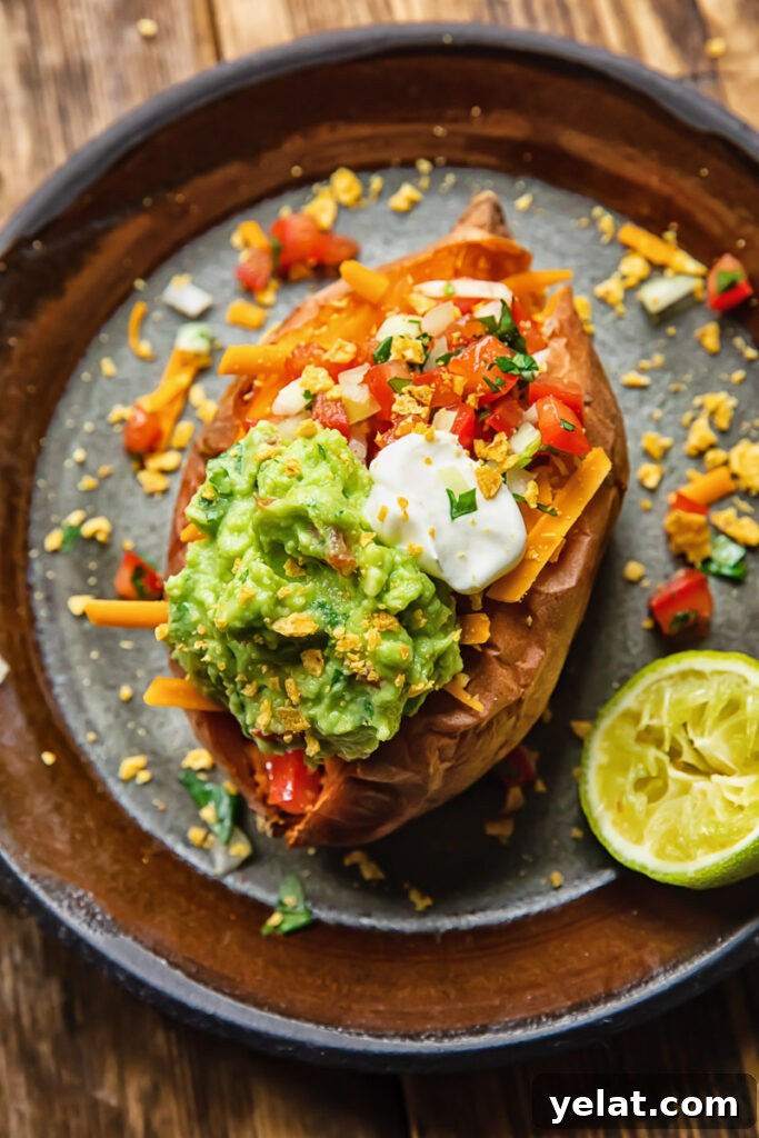 Crispy Air Fryer Sweet Potato (Simple Baked Style) 4 Top down shot of baked sweet potato on a plate topped with pico de gallo and guacamole