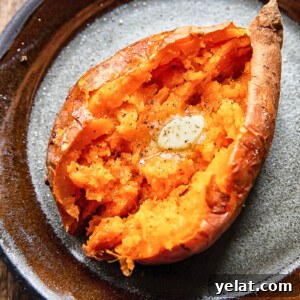 Crispy Air Fryer Sweet Potato (Simple Baked Style) 5 Close up shot of a cut open baked sweet potato topped with melted butter on a plate