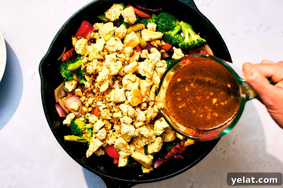 Spicy Kung Pao Tofu with Stir-Fried Vegetables 11 Sauce being poured on top of Kung Pao Vegetables with Tofu in a skillet.