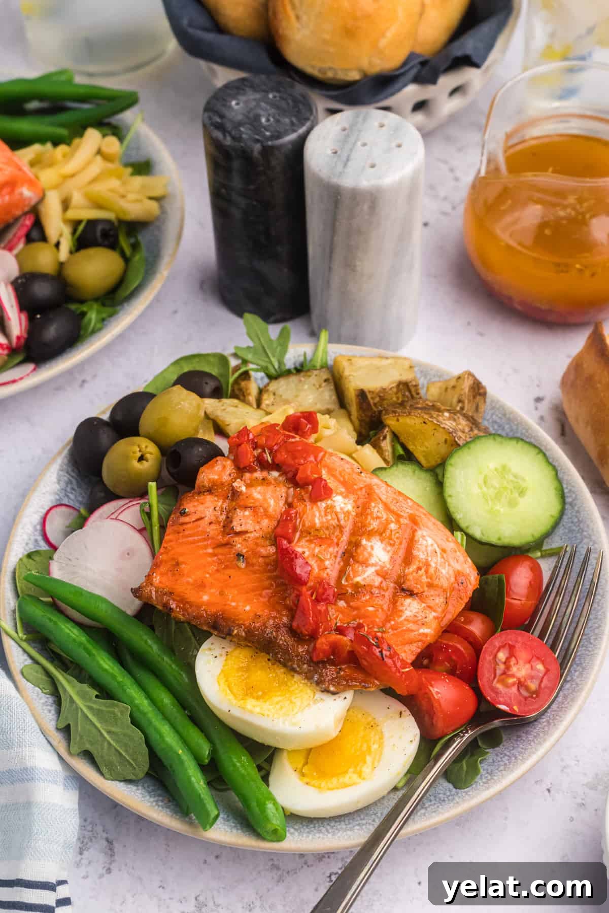 Salmon Nicoise Salad on a dinner plate with salt and pepper in the background.