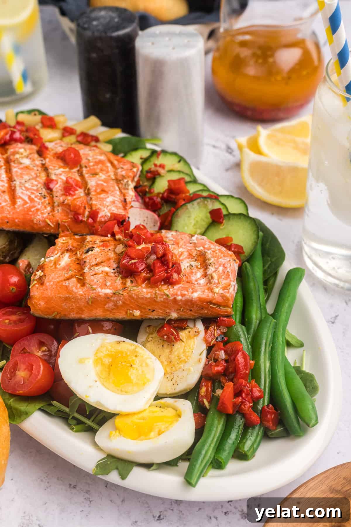 Side view of salmon Nicoise salad with hard boiled eggs, green beans and a roasted red pepper dressing.