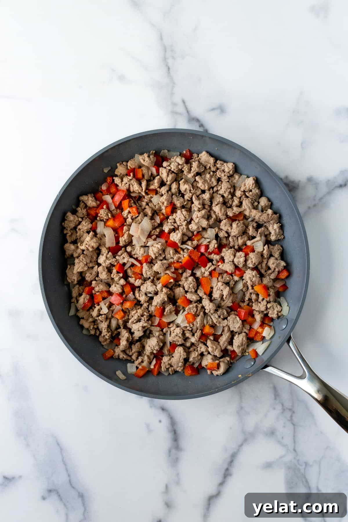 Sweet Potato and Turkey Hash with Spinach & Herbs 4 Browned ground turkey, onions, and peppers in a skillet on a marble countertop.
