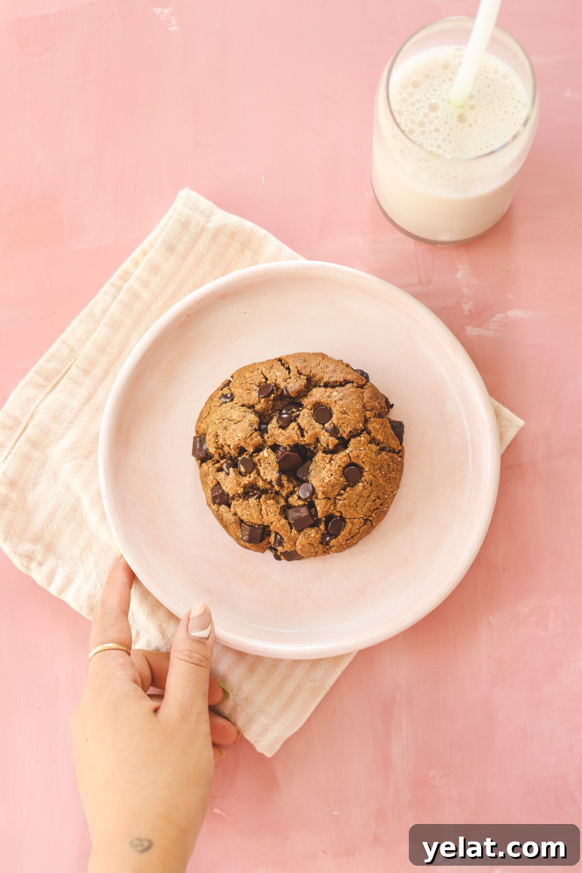 a hand holding a plate with a cookie on it. 