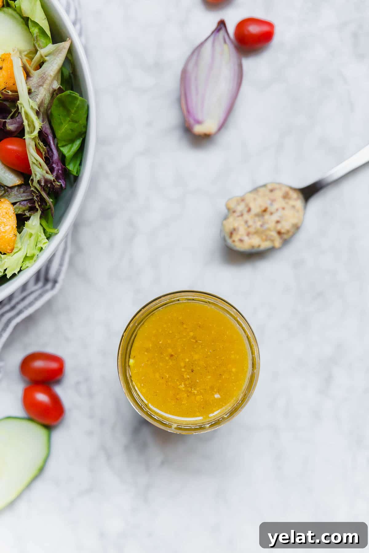 Creamy Honey Mustard Vinaigrette Recipe for Salads & Marinades 4 A Jar of honey mustard vinaigrette with a spoon of ground mustard, a salad, shallot and tomatoes.