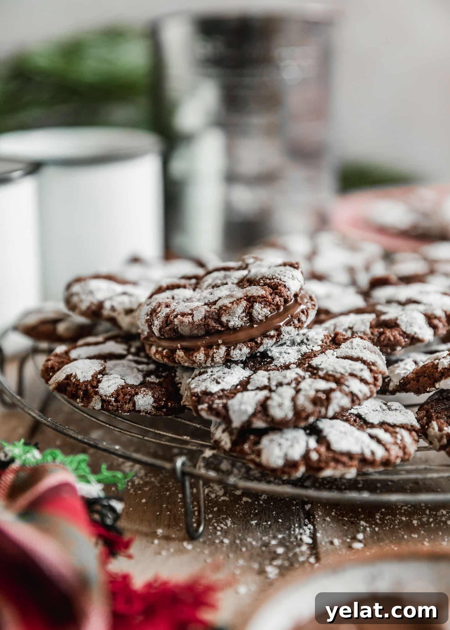 Fudgy Mocha Crinkle Cookies Recipe for Rich Chocolate Coffee Cookies 7 Mocha crinkle cookie sandwiches on a wire rack next to white mugs of coffee, a white bowl of Nutella, and a red linen with a wood background.