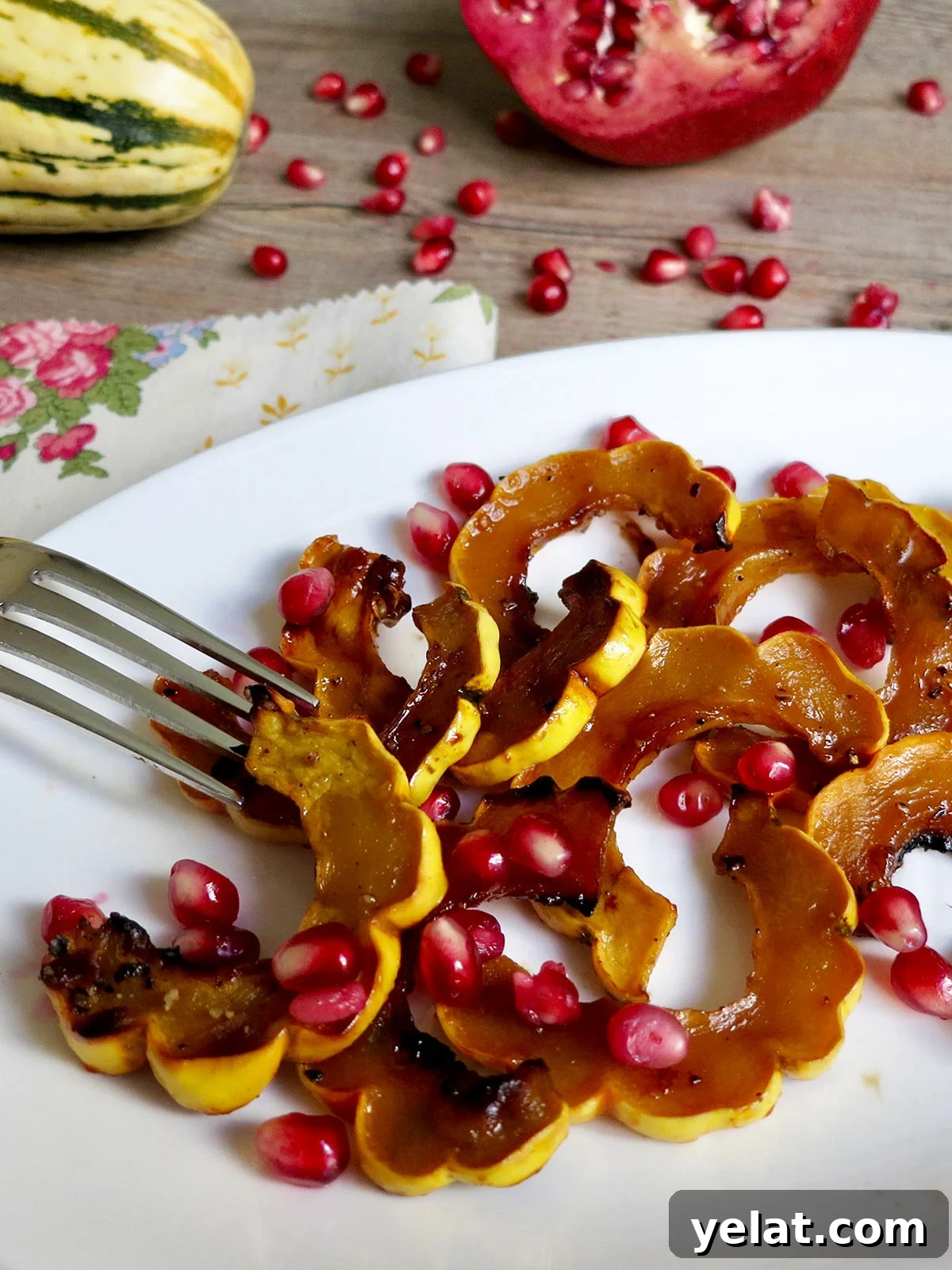 Roasted Delicata Squash with Pomegranate Molasses & Date Syrup 2 Roasted delicata squash on white plate with fork and pomegranate seeds.