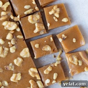 caramels topped with chopped walnuts on white parchment paper.