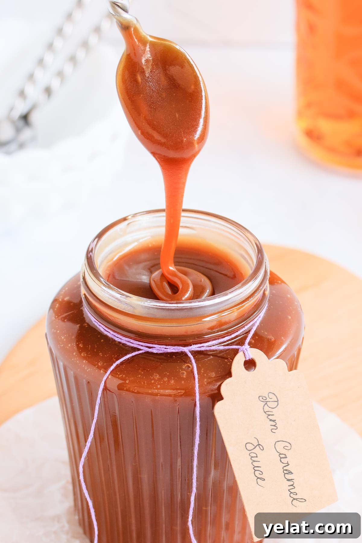 Homemade Rum Caramel Sauce Recipe for Desserts and Drizzling 2 Caramel sauce in a ribbed glass jar with a spoon, text overlay reads "rum caramel sauce".