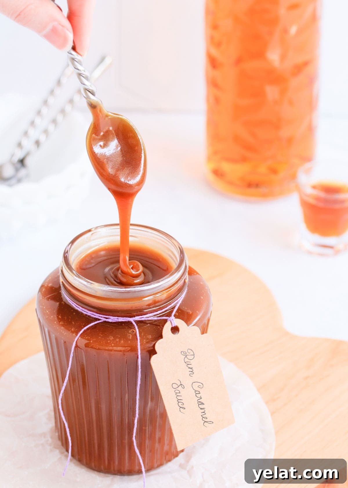 Homemade Rum Caramel Sauce Recipe for Desserts and Drizzling 13 Rum caramel sauce falling from a spoon in a thick ribbon back into a ribbed glass jar.