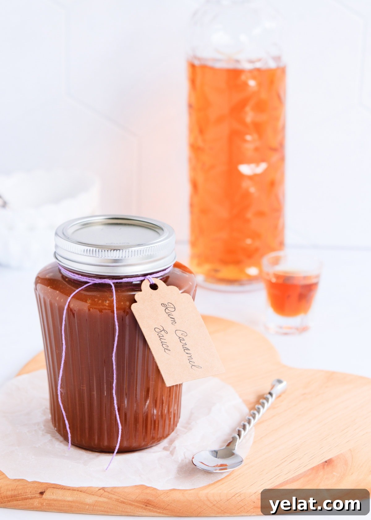 Homemade Rum Caramel Sauce Recipe for Desserts and Drizzling 3 Rum caramel in a ribbed glass jar with a silver lid and a hand written label tied on with purple twine.