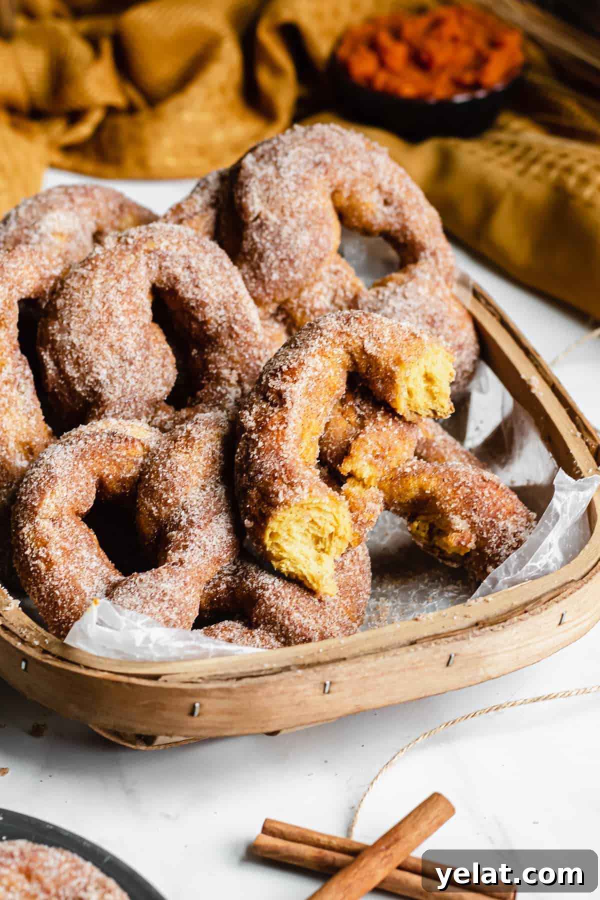 Basket of pumpkin spice soft pretzels. One pretzel is ripped in half to show the orange color inside.