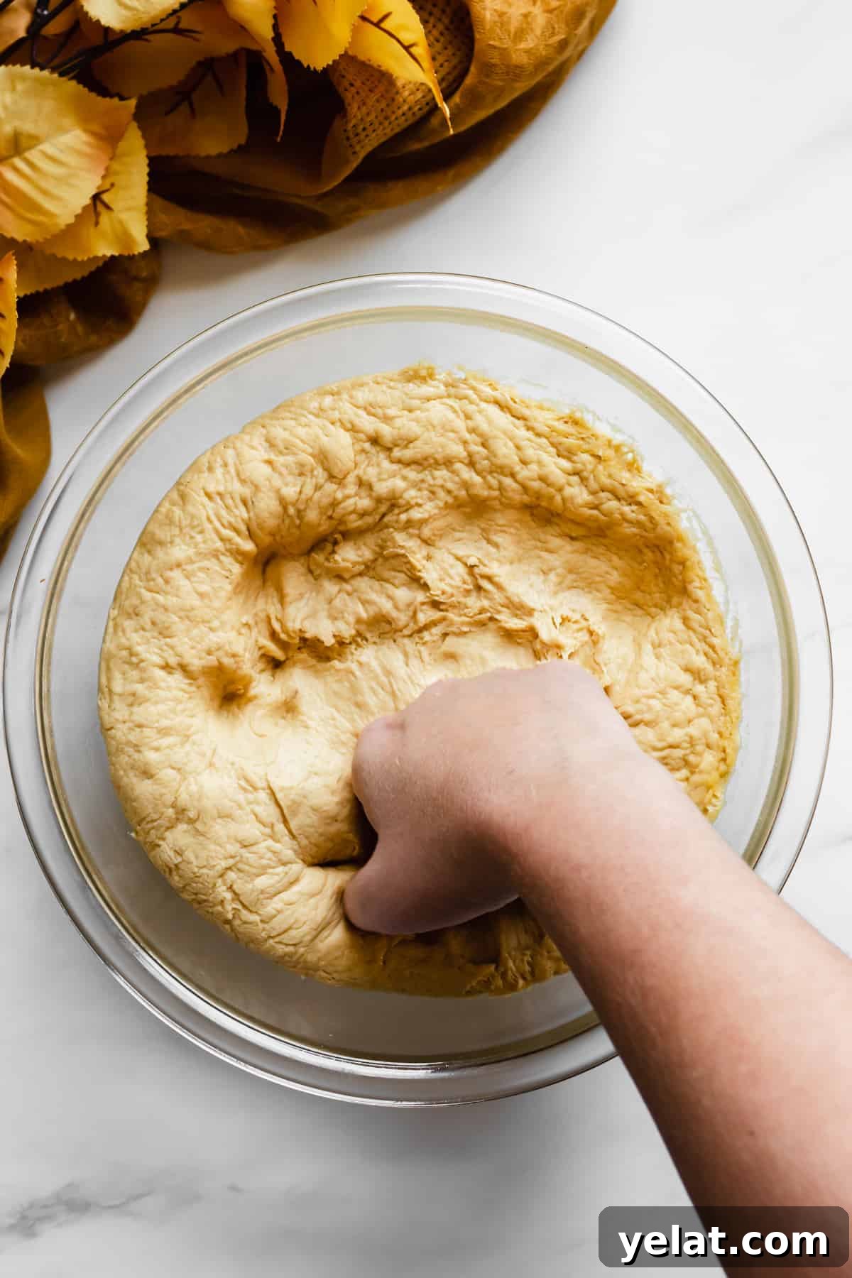 A hand punches down the dough.