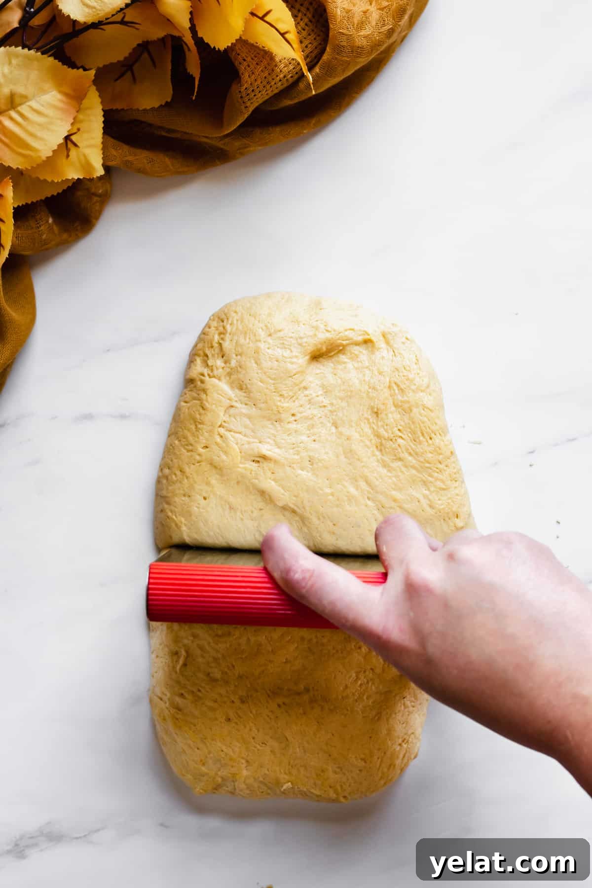 Dough being cut into pieces using a bench scraper.