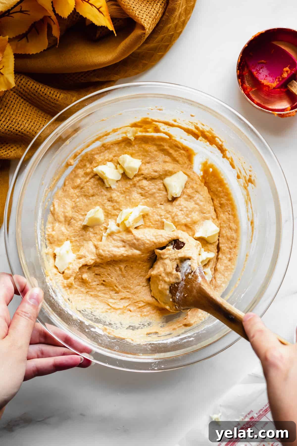 Softened butter being stirred into the pumpkin spice soft pretzel dough.