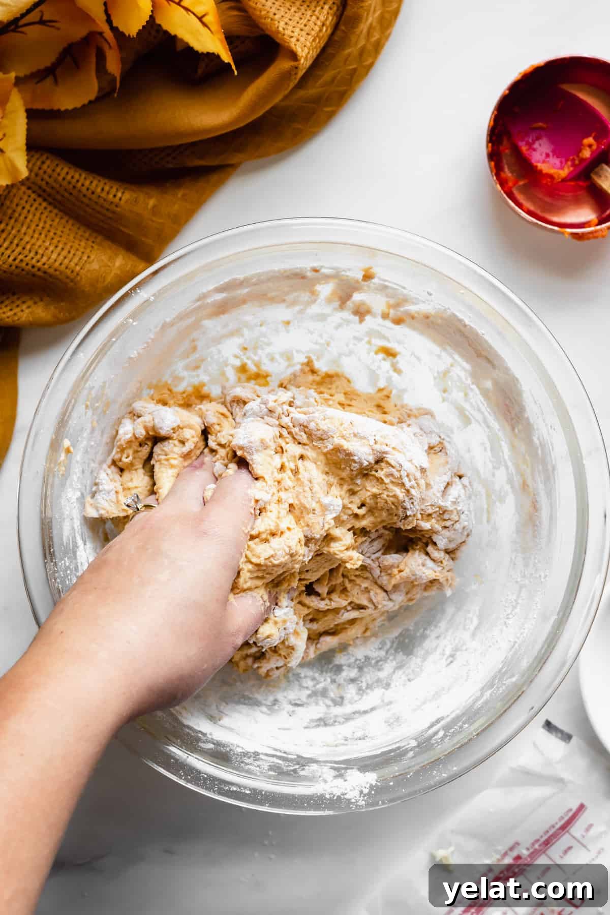 A hand words the pretzel dough together in the bowl.