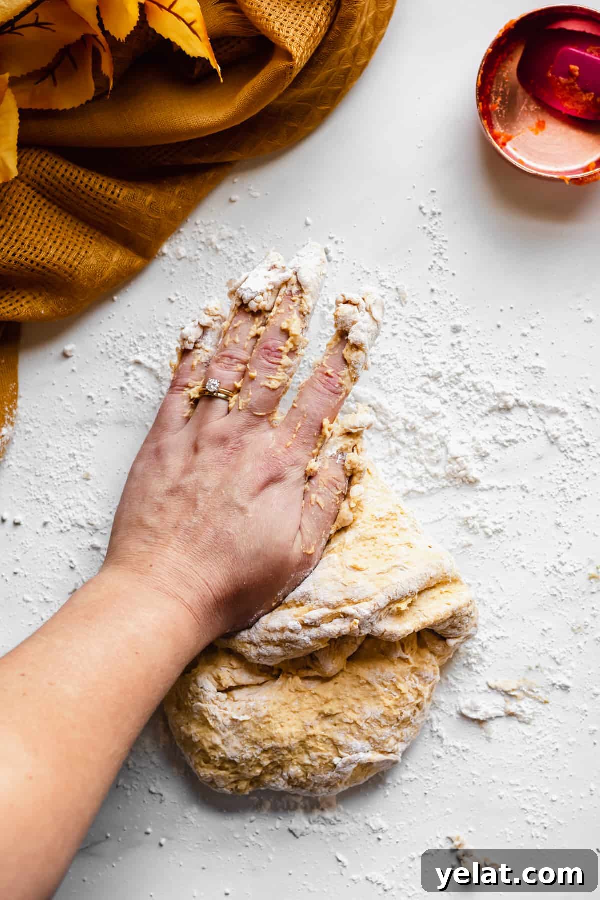 A hand kneads the pumpkin soft pretzel dough.