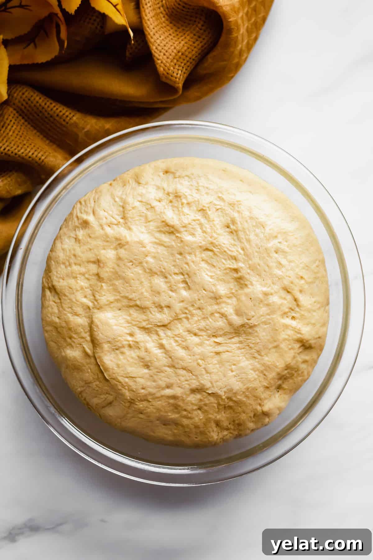 Risen pumpkin soft pretzel dough in a bowl.