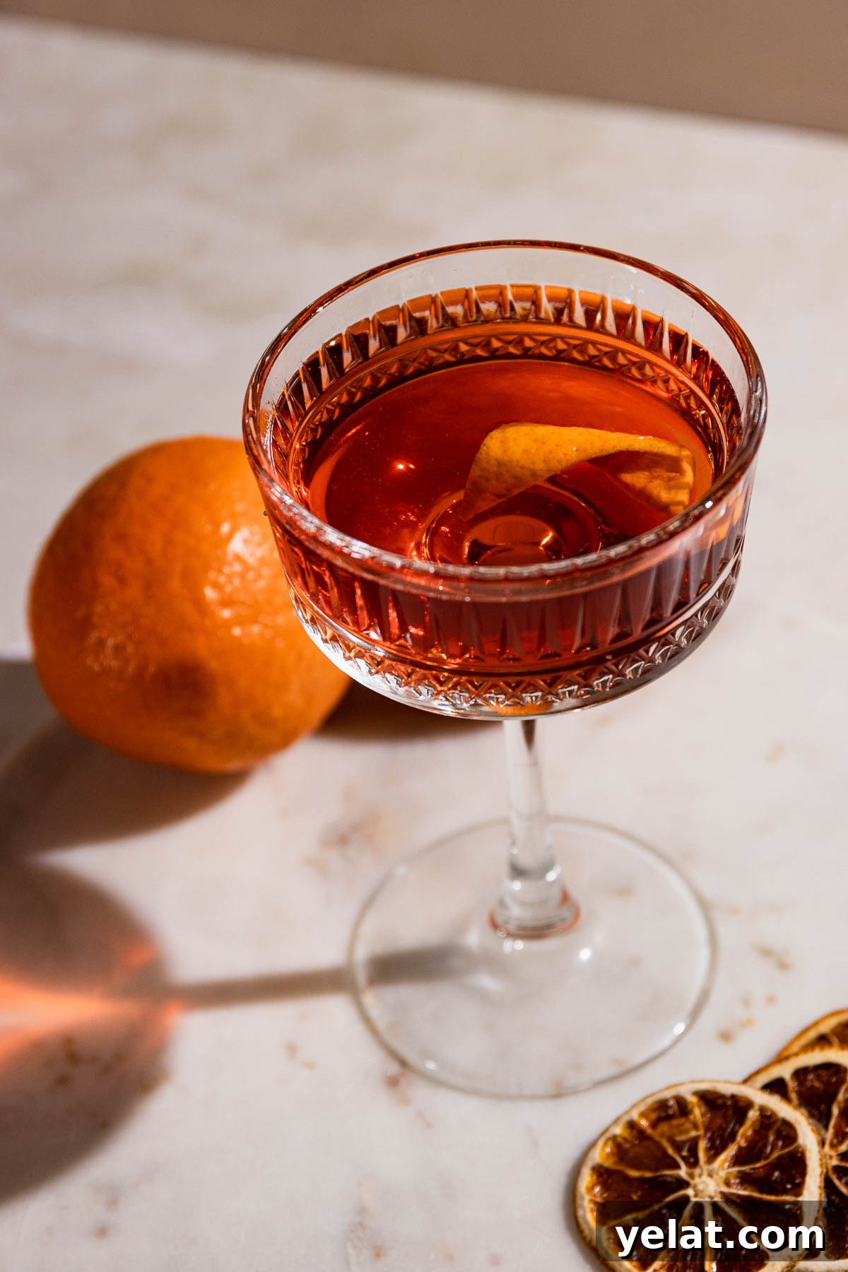 Looking into a cocktail glass to an el presidente cocktail with an orange twist garnish. 