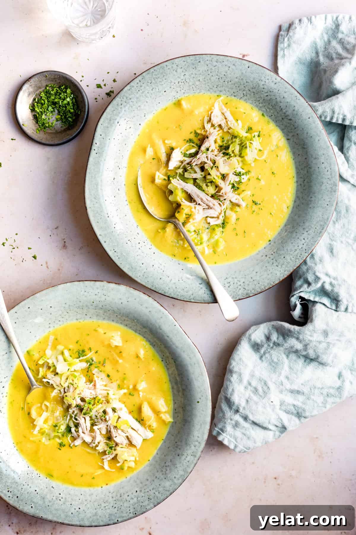 Chicken and leek soup in a blue bowl with a spoon.