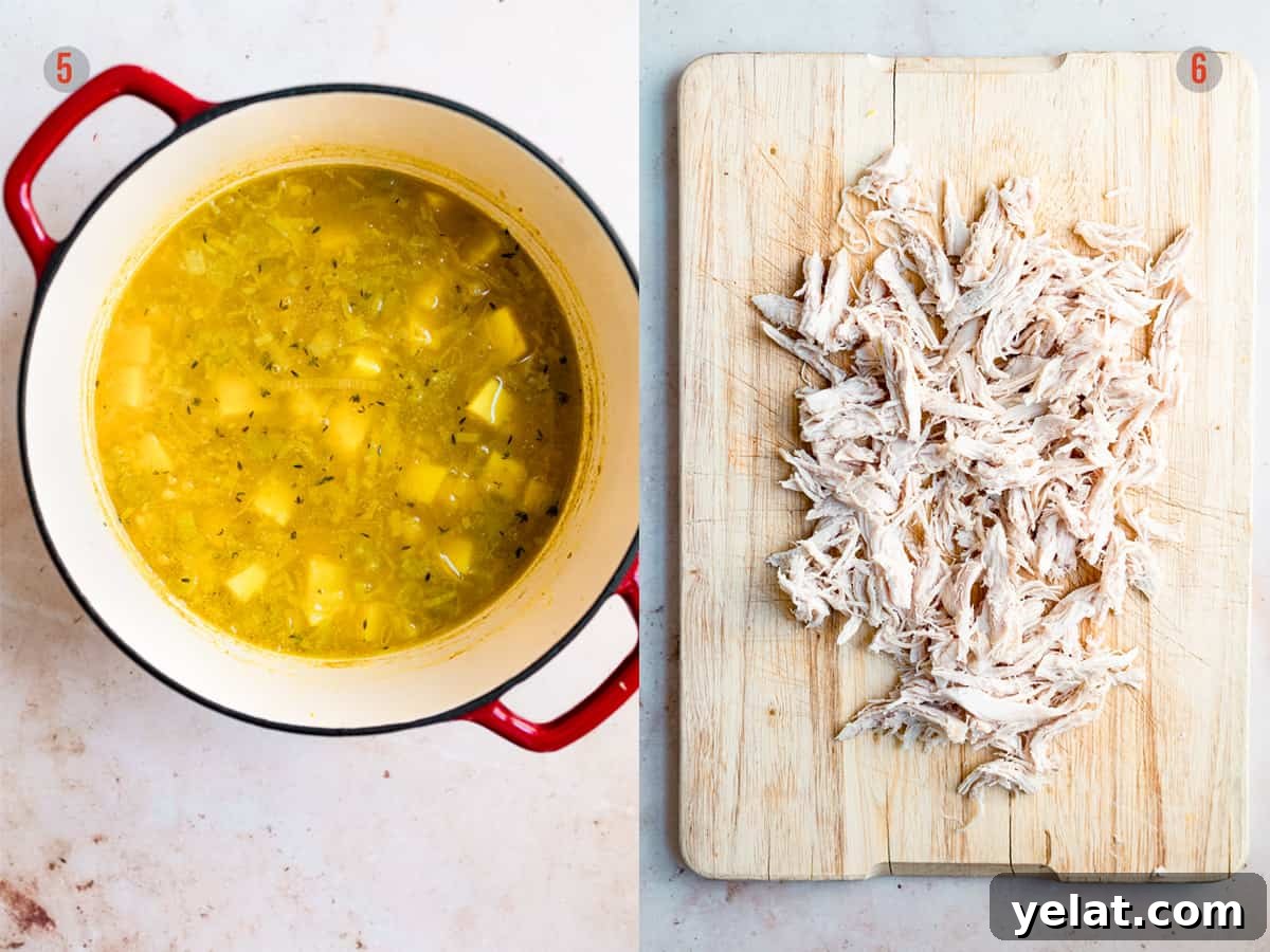 poached chicken being shredded with a fork on a board.