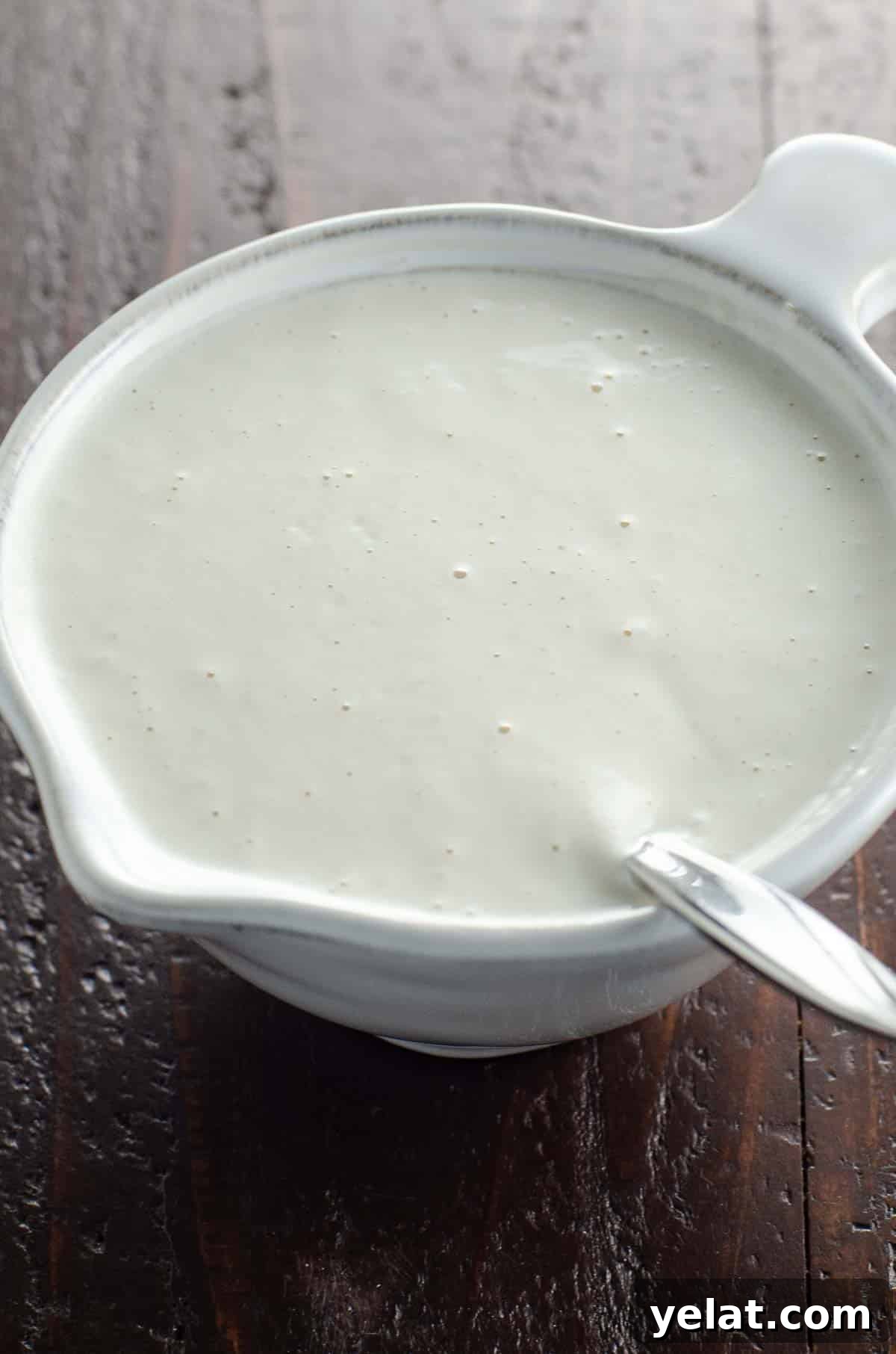 vegan cashew cream in a small pitcher with a spoon