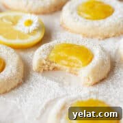 Lemon Curd Thumbprint Cookies — Zesty Homemade Cookie Recipe 11 A bitten lemon curd cookie on a piece of parchment paper.