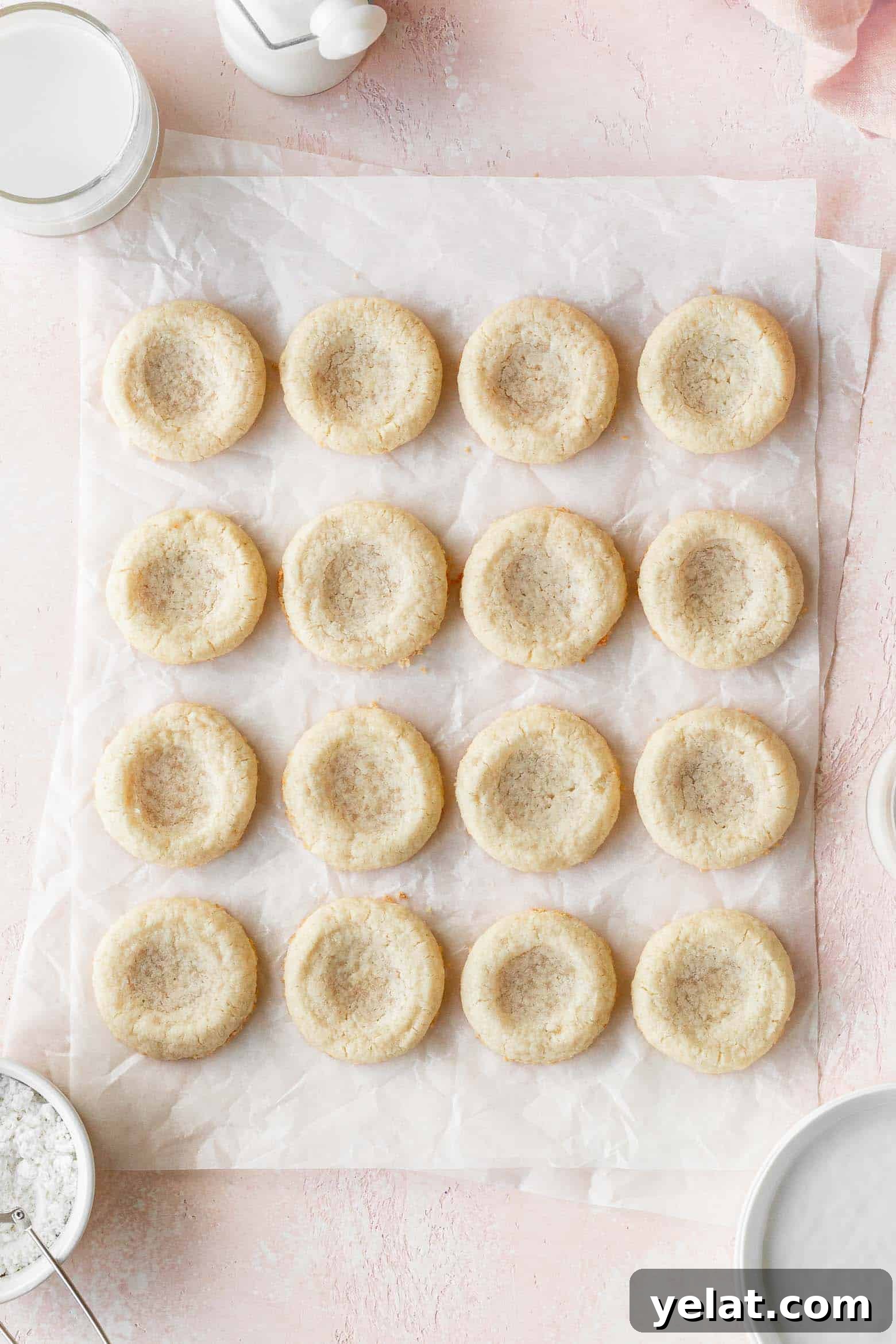 Lemon Curd Thumbprint Cookies — Zesty Homemade Cookie Recipe 6 Sugar cookies with indentations on a piece of parchment paper.