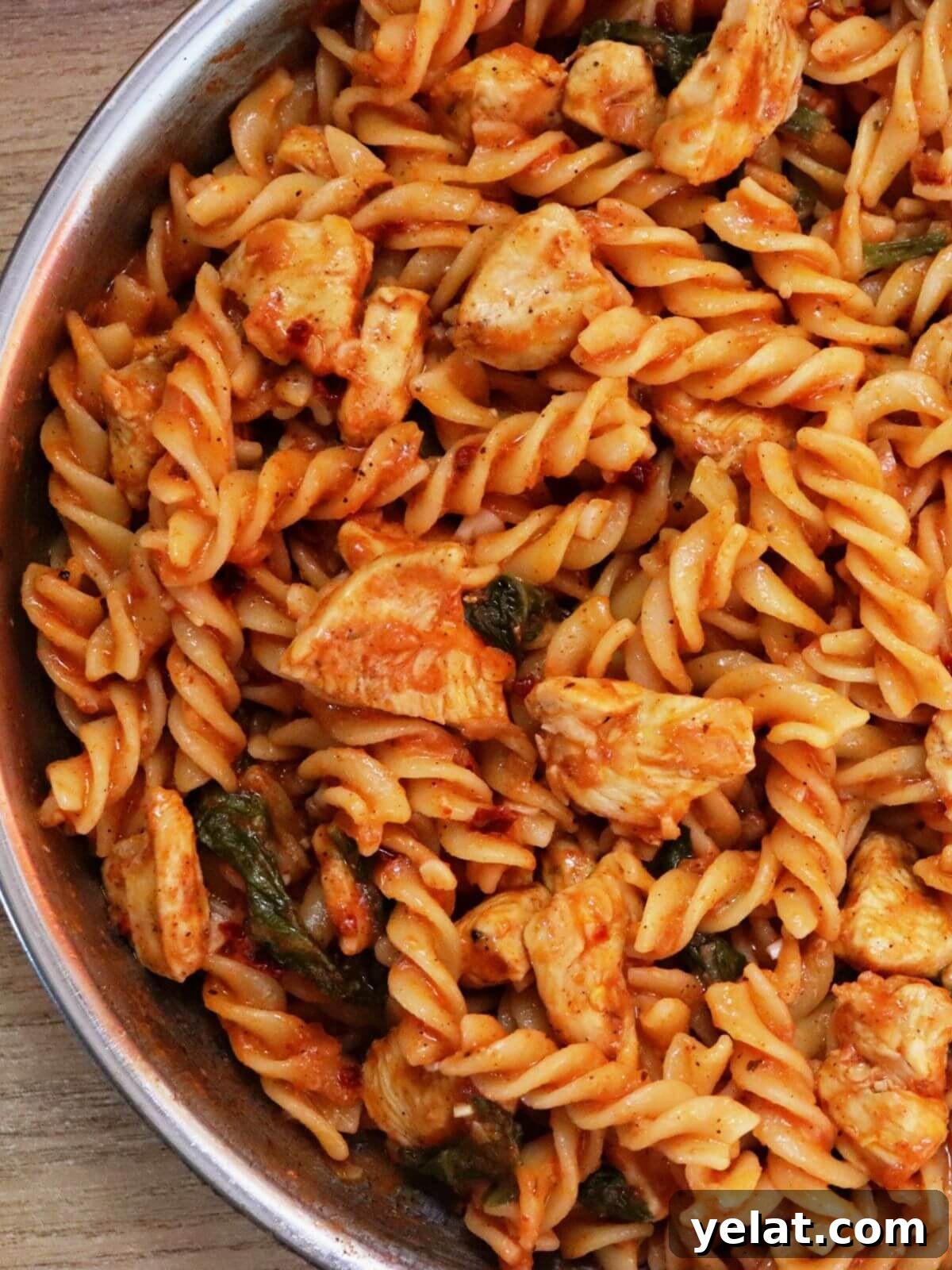 Creamy Tomato Spinach Chicken Pasta Recipe 2 close-up of tomato spinach chicken pasta in a skillet.