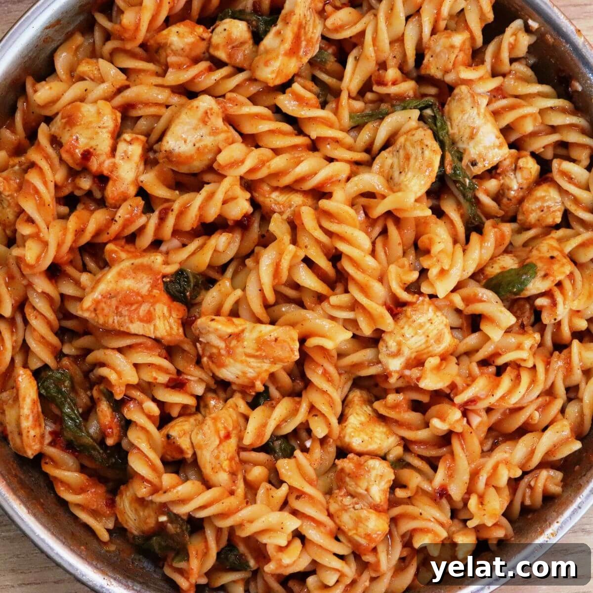 tomato spinach chicken pasta in a skillet.