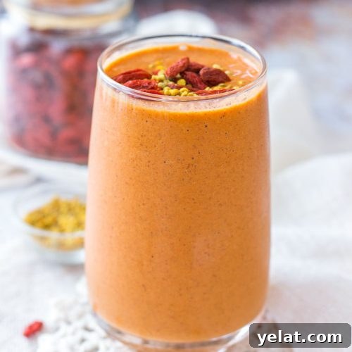 Goji Berry Smoothie served in a tall glass topped with goji berries and bee pollen