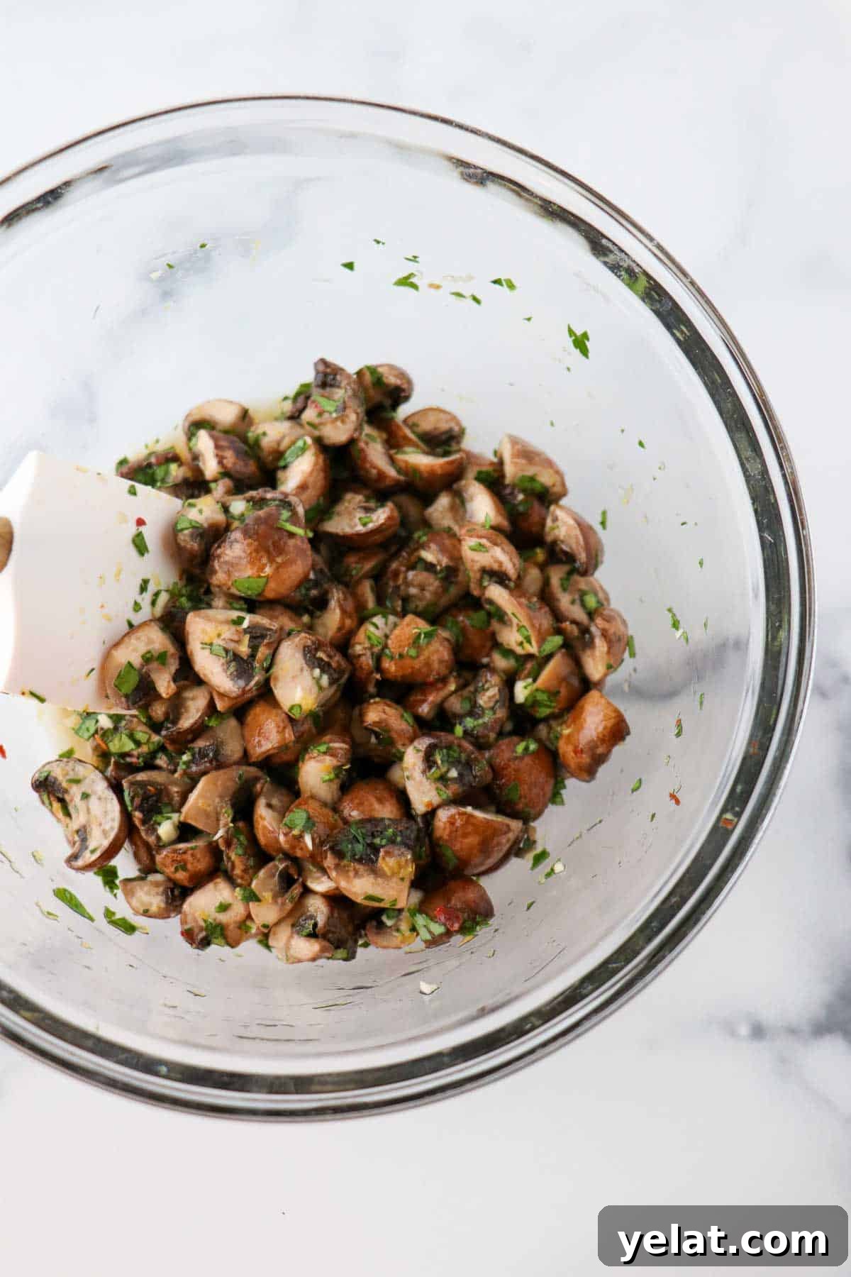 Quick Pickled Mushrooms: Fast Tangy Recipe for Snacks and Sides 7 Quick pickled mushrooms in a glass bowl with a white rubber spatula.