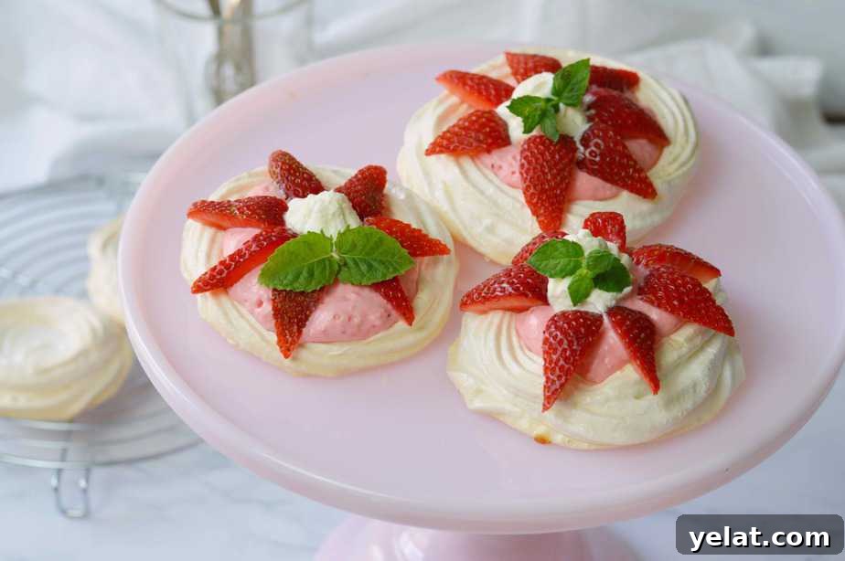 Light and Creamy Strawberry Mousse Pavlovas Recipe 6 strawberry mousse pavlova on pink pedestal.